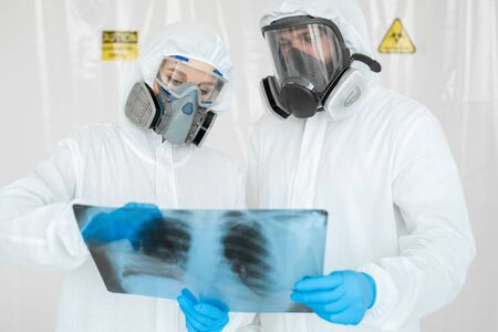 Epidemiologists in respirators examine the patients pneumonia on a radiograph Covid-19. Concept of...