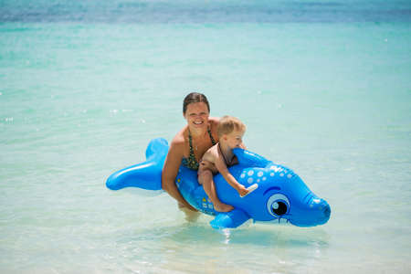 Mother and son swimming in the ocean on an inflatable Dolphin.の写真素材