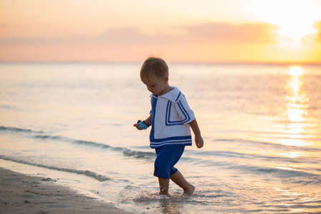 Boy on the beach. Wooden boat on the horizonの写真素材