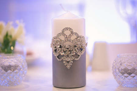 Wedding decor in silver style with crystals, lace and flowers. Wedding candles for the family hearth.の写真素材