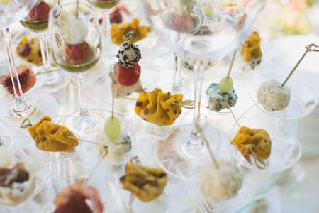 Reception at the wedding. Snacks and wine glasses on a glass tableの写真素材