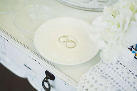 Wedding rings on a ceramic white saucer.の写真素材