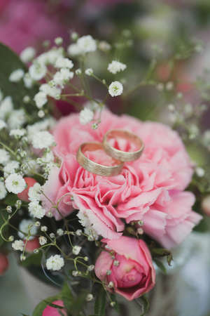 Gold wedding rings on a bouquet of fresh flowersの写真素材