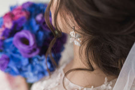 Delicate wedding hairstyle. Long dark curly hair. Elegant gathered hair. The bride in a white dress...