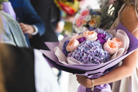 A very nice young woman is holding a large and beautiful bouquet. A wedding gift for the bride