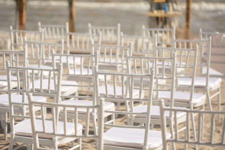 Outdoor area for beach ceremonies with sea view, white chairs, flower arch on a sunny day.の写真素材