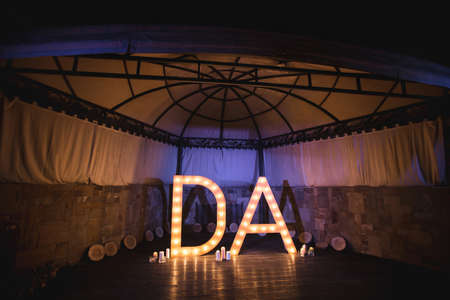 Wooden initials of the bride and groom with bright lights at the weddingの写真素材
