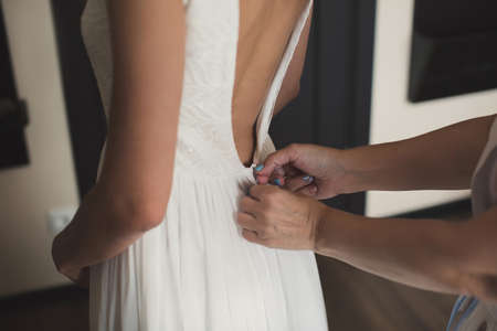 A friend helps to dress the brides wedding dress.の写真素材