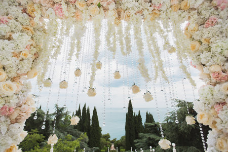 Wedding arch with flowers and beads on blue sky background close-upの写真素材