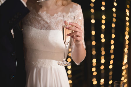 The bride and groom hold crystal glasses filled with champagne.の写真素材