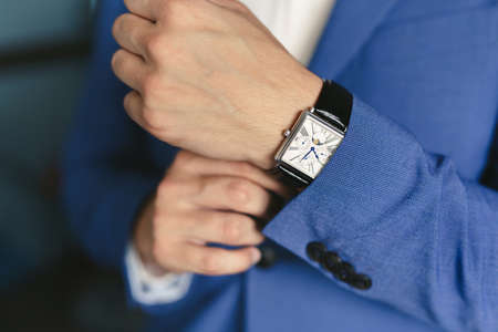 Close-up hands of the groom with a clock.の写真素材