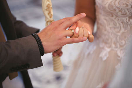 The groom puts the ring on the brides finger in close-up.