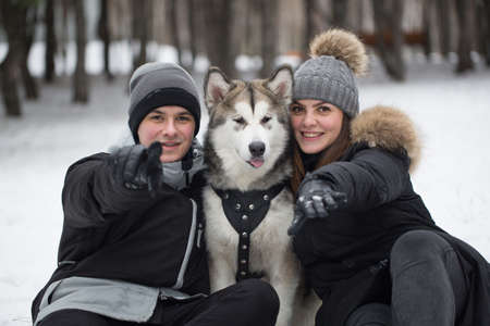 Beautiful family, a man and a girl in winter forest with dog. Play with the dog Siberian husky