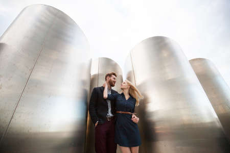 Man and woman pose in front of the large metal pipes.