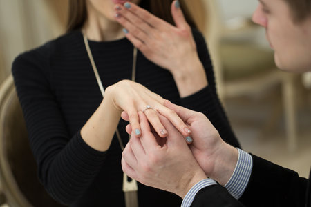 Close Up Of Male Hand Inserting An Engagement Ring Into A Finger.の写真素材