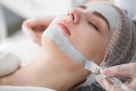 Face peeling mask, spa beauty treatment, skincare. Woman getting facial care by beautician at spa...