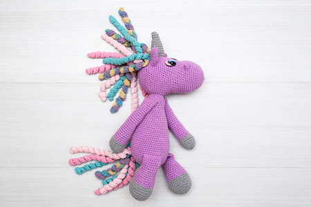 A knitted unicorn with a multicolored mane. A toy for a childの写真素材