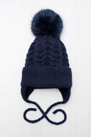 Childrens knitted wool hat with a pompom, on a white background.