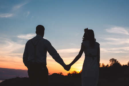 Loving couple together outdoor in mountains over scenic sunset sky backgroundの写真素材