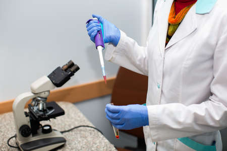 A scientist working with blood samples and a microscope in the laboratory.