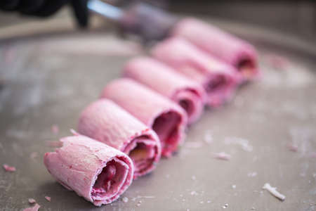 Stir-fried ice cream rolls at freeze pan. Rolled ice cream, hand made ice cream dessert. Fried ice cream machine with steel chilled panの写真素材