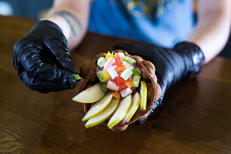 Cook prepares Hong Kong waffles with ice cream, jam and fruit. Young woman holding Hong Kong bubble wafers.の写真素材