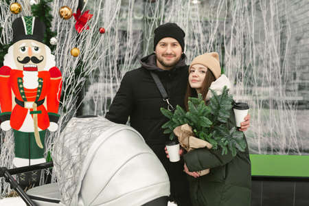 Portrait of a young family, a man and a woman with a stroller on a walk on a winter dayの写真素材
