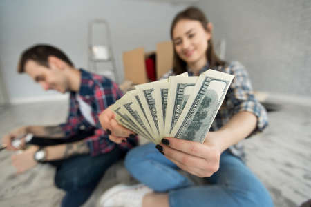 Young couple counting money while sitting on floor in new apartment.の写真素材