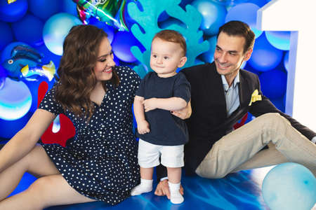 Father, mother and son on the background of blue decor in the marine style at the holiday
