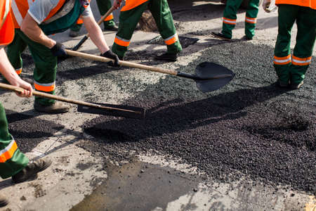 Workers on Asphalting paver machine during Road street repairing works. Street resurfacing. Fresh...