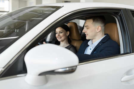 Married couple husband and wife sitting in a car in a car dealership. Test the car before buyingの写真素材
