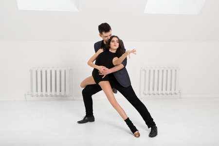 beautiful couple dancing bachata on white background in studio.