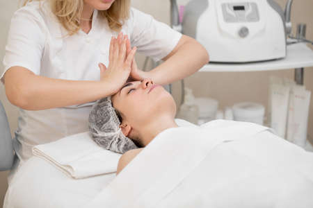 Woman beautician makes a professional massage to a young girl. Beauty treatments for skin care in the SAP salon. Health facial masseur. Relax cosmetology procedure.の写真素材