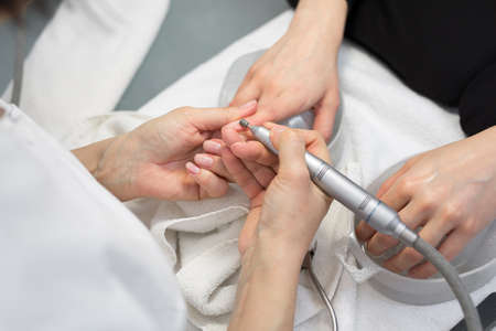Manicurist doing hardware manicure to a young beautiful girl in the spa salon. Hardware manicure. Concept of body care.の写真素材