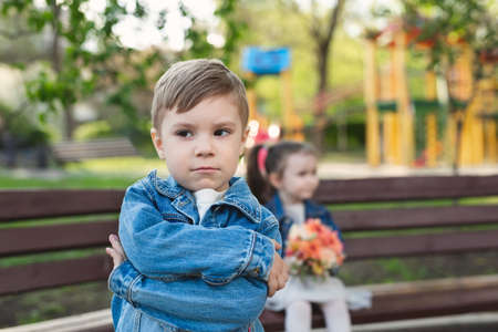 Date of a little boy and a girl in the park with a bouquet of flowers. The boy was offendedの写真素材