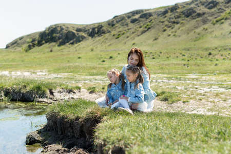 Mother with twin daughters resting near the river in the villageの写真素材