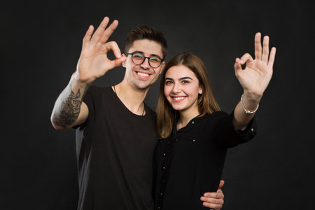 Couple making OK sign on black background.の写真素材