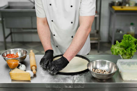 Chef is working in the kitchen with pizza dough.
