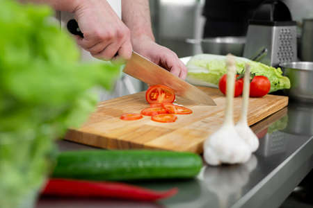 Chef in the kitchen cuts fresh and delicious vegetables for a vegetable salad.の写真素材