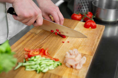 Chef man cutting chili peppers at table, closeup.の写真素材