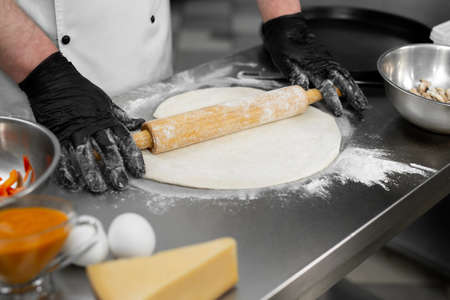 Close up shot of a man rolling dough. Preparation of the dough for pizza.の写真素材