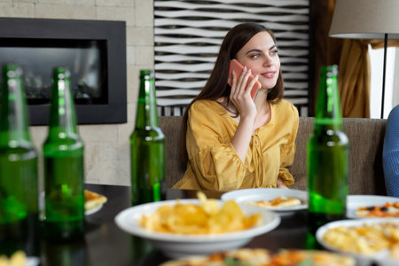 Young woman drinking beer and talking on mobile phone.の写真素材