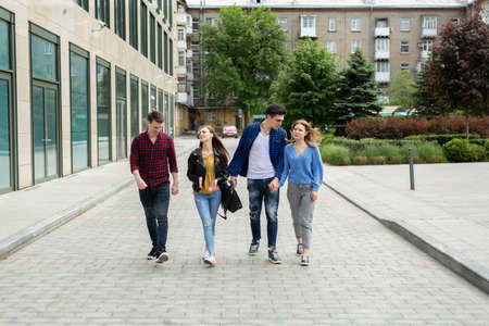 Friendship, travel and vacation concept - group of smiling friends walking in the city.