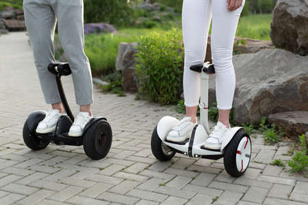 Legs of man and woman riding on the Hoverboard for relaxing time together outdoor at the city.の写真素材
