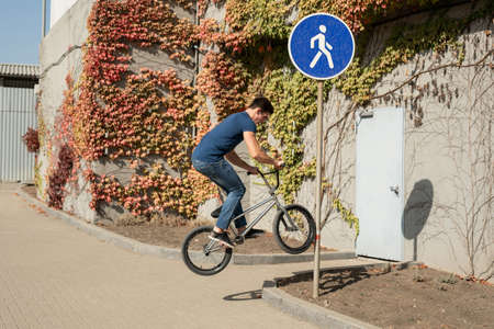 Teenage BMX rider is performing tricks in skatepark.