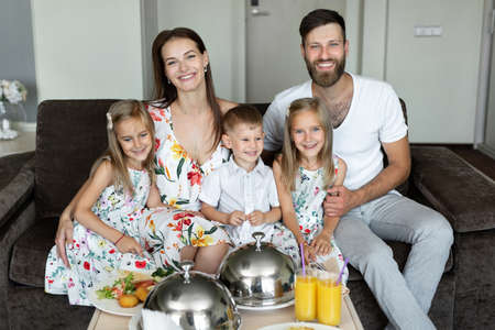 A young family eats breakfast in the hotel room.の写真素材