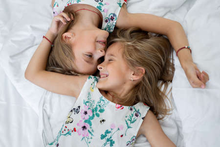 Two twin sisters are lying on the bedの写真素材