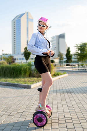 Portrait of a beautiful woman on a hoverboard or gyro scooter in the park.