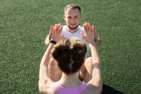 Man and a woman pump their abs in the park on the grass.の写真素材