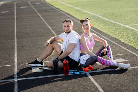 Man and a woman sit in the stadium and laugh. Outdoor sports activities.の写真素材